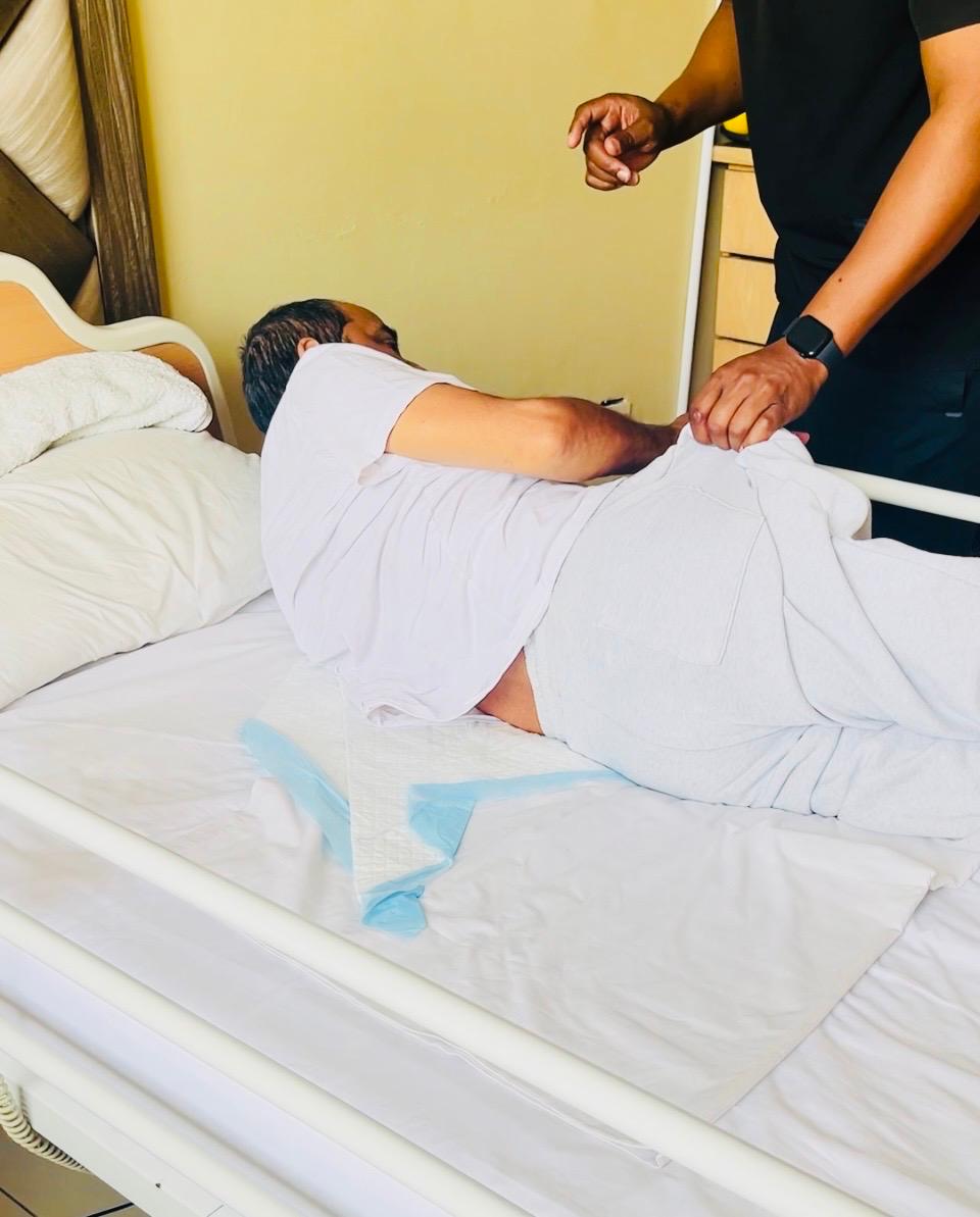 A physiotherapist guiding a patient's arm exercise during a bedside session